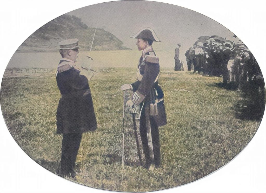 König Alfons in Admiralsuniform läßt sich ein Schiffsmanöver erklären